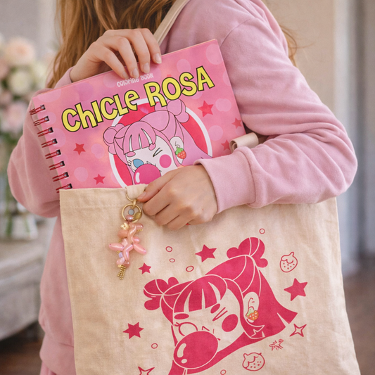 Persona con polerón rosado sostiene el libro para colorear Chicle Rosa junto a una totebag beige ilustrada de Javipinkk.
